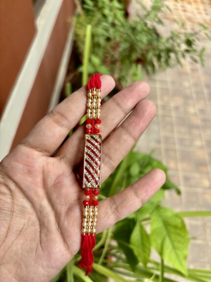 Fancy red thread rakhi with a central AD bracelet centerpiece