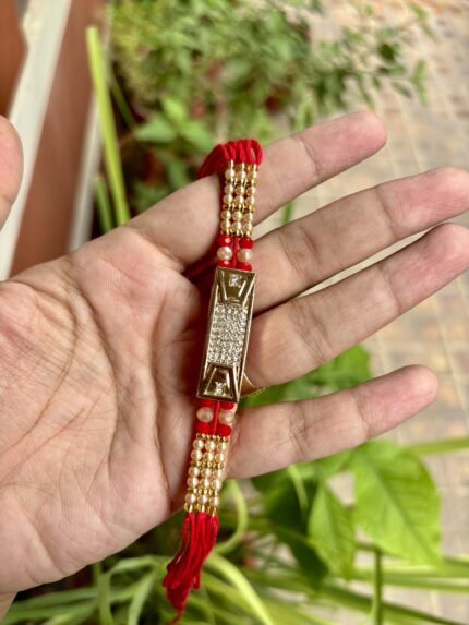 Fancy red thread rakhi with a central AD bracelet centerpiece
