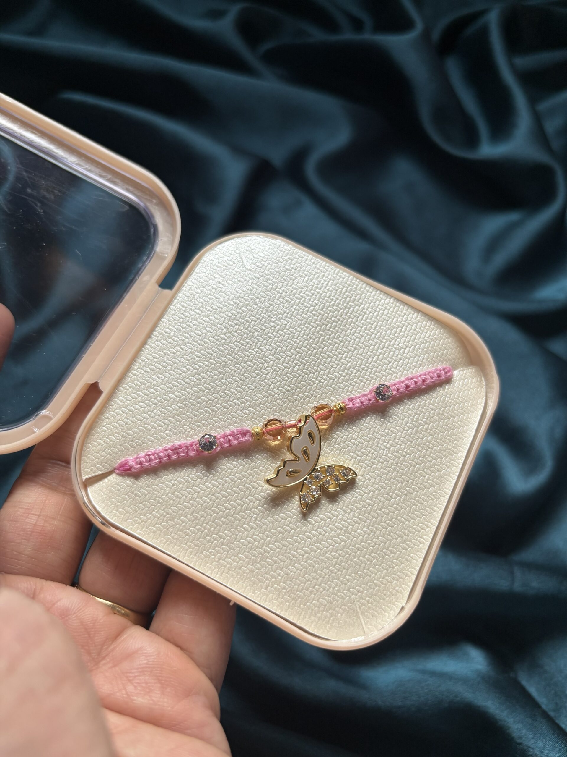 Pink thread Rakhi with a central butterfly motif
